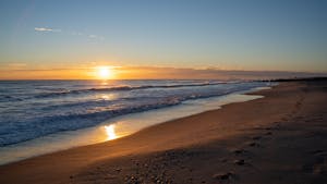 Capture of a serene sunrise along the Valencia beachfront, showcasing golden reflections on the sea.