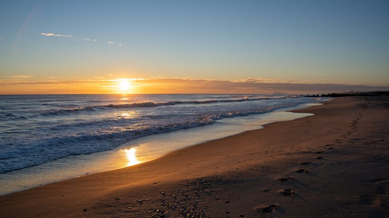 Capture of a serene sunrise along the Valencia beachfront, showcasing golden reflections on the sea.